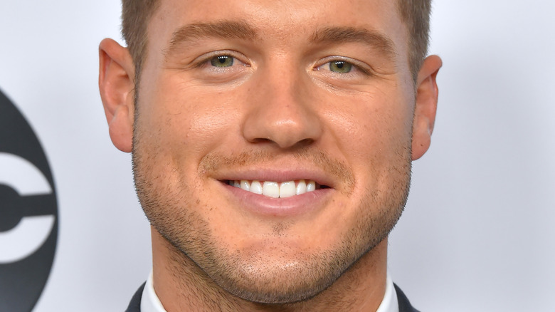 Colton Underwood smiles in a suit and tie