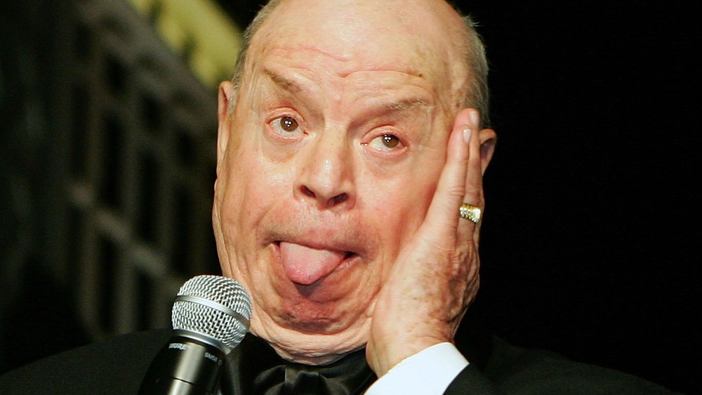 Comedian Don Rickles sticking his tongue out while at the mic