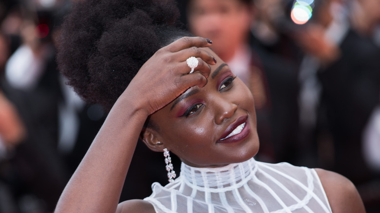 Lupita Nyong'o places her hand on her head