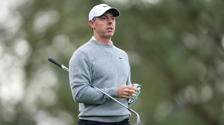 Rory McIlroy on with a golf club under one arm on the course.