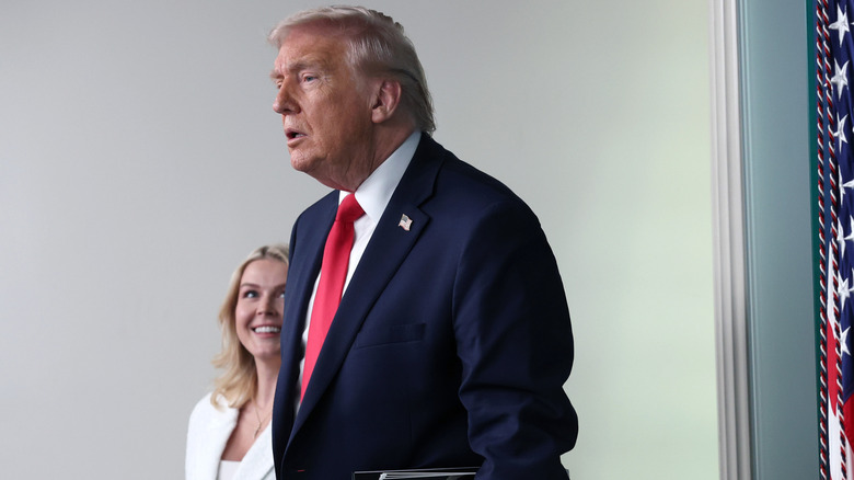 Karoline Leavitt gazes at Donald Trump as he enters the White House press room.