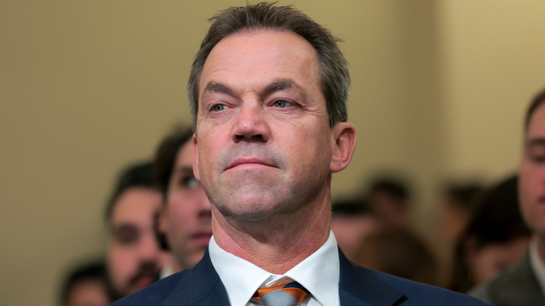 Bryon Noem pictured in late 2025 in a navy suit with an orange patterned tie