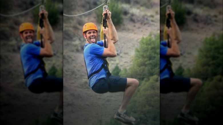 Bryon Noem ziplining while sticking his tongue out in a blue T-shirt and orange helmet