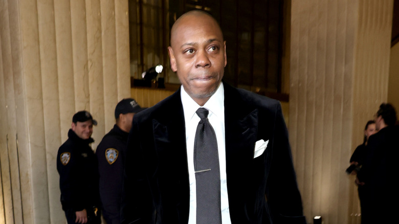 Dave Chappelle standing outside a building.