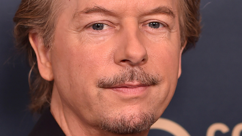 David Spade poses in a black shirt