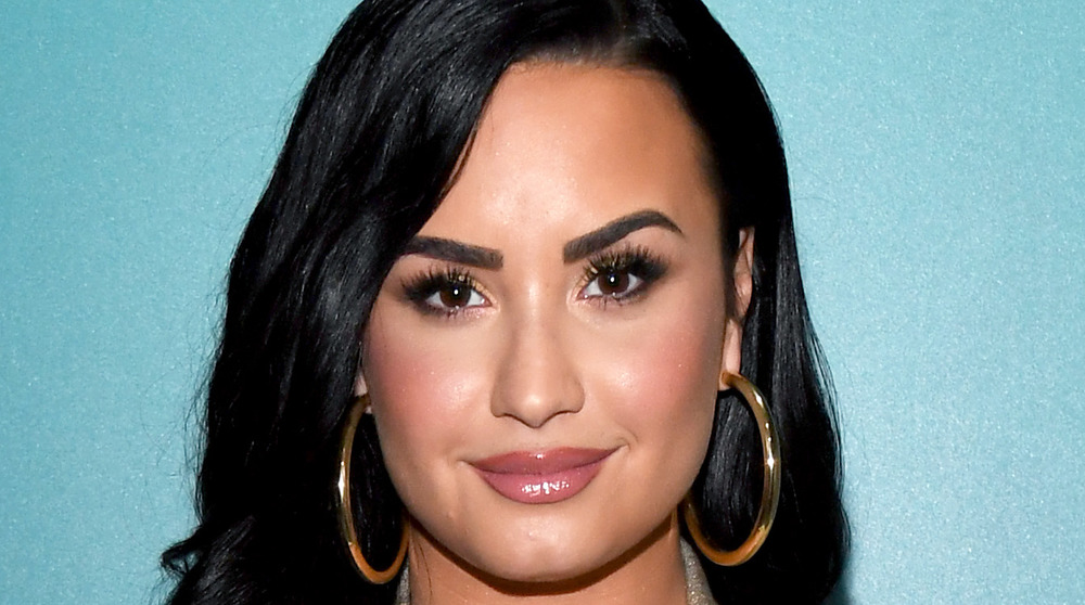 Demi Lovato smiling while wearing hoop earrings