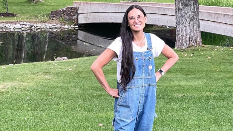 Demi Moore smiling outdoors in denim overalls