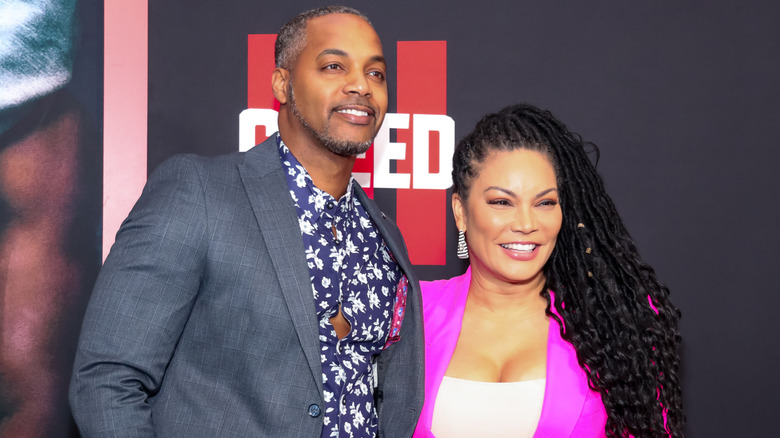 Mike Jackson wearing a floral shirt and gray blazer and posing with Egypt Sherrod, who is wearing a pink blazer, on the red carpet