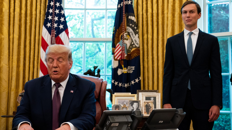 Jared Kushner standing over Donald Trump