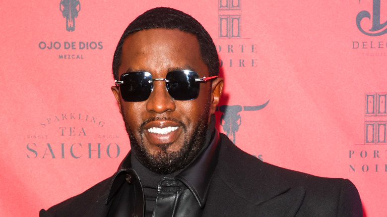 Diddy smiling in front of red backdrop