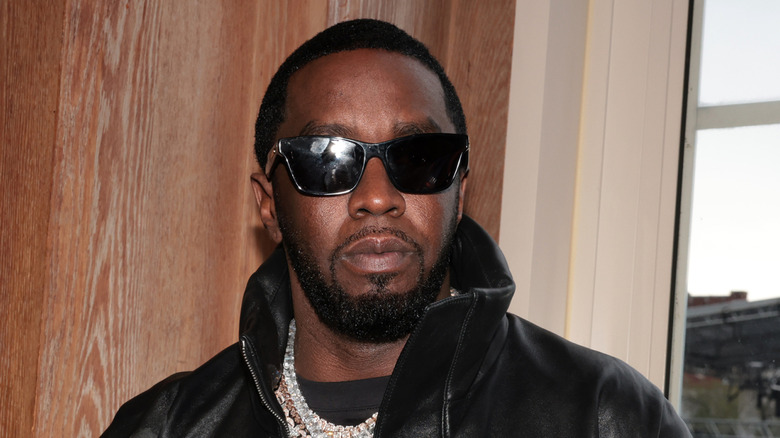 Diddy posing in sunglasses and black clothes at Howard University.