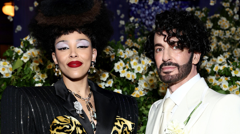Doja Cat wearing a black and silver striped jacket with a leopard print bustier with Marc Jacobs wearing a white suit, white collared shirt, and white tie