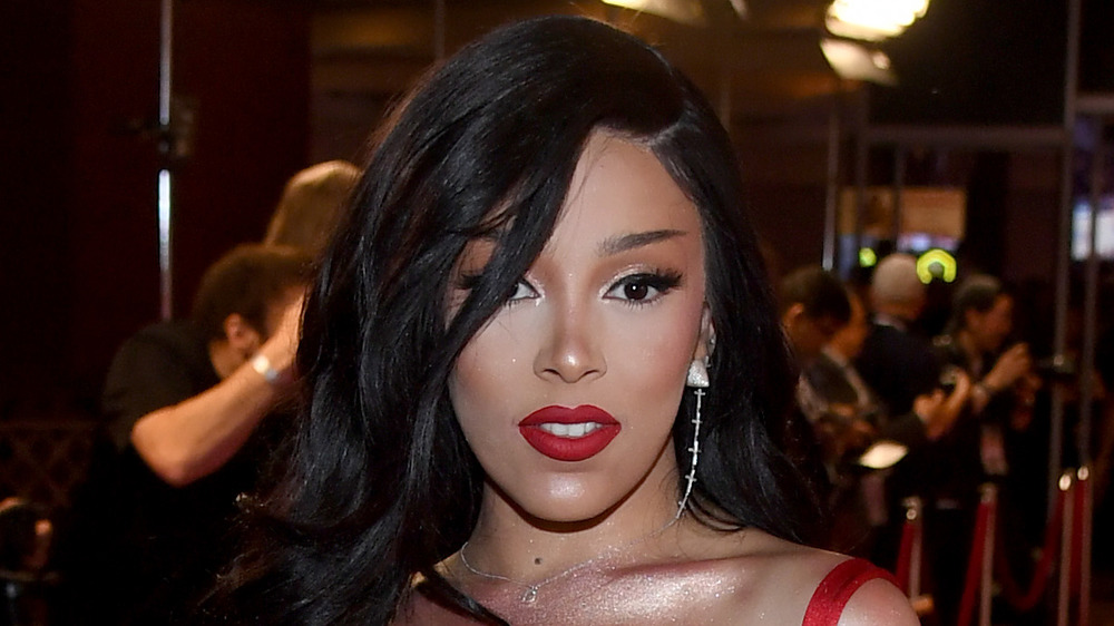 Doja Cat, in red lipstick, smiles on the red carpet 