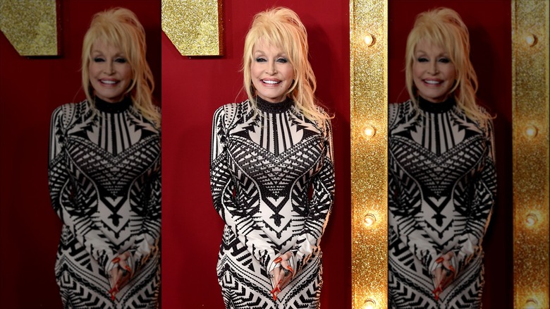 Dolly Parton posing and smiling in a black and white patterned dress