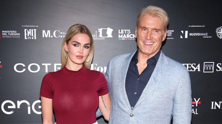 Emma Krokdal and Dolph Lundgren posing at an event with their arms around each other's backs