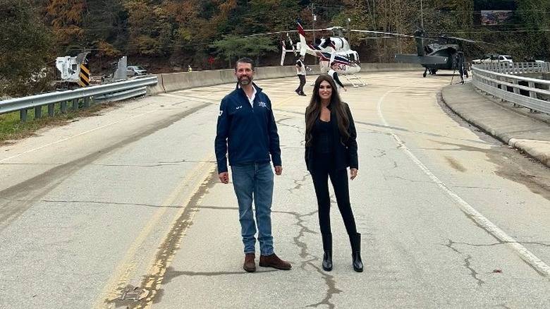 Don Jr. and Kimberly Guilfoyle posing in the middle of a road with helicopter behind them