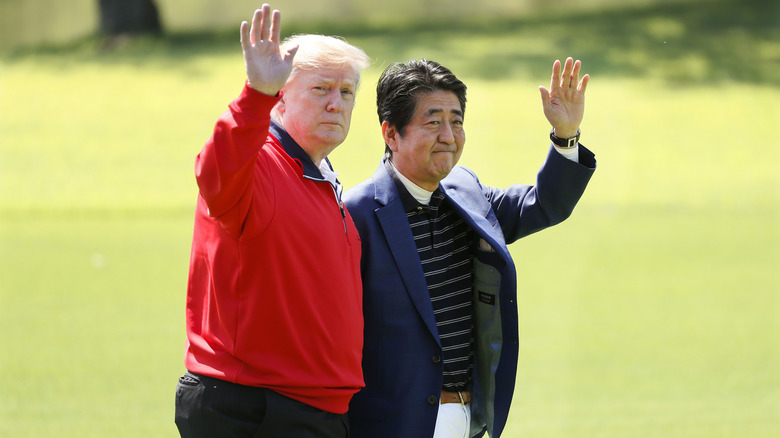 U.S. President Donald Trump and Japanese Prime Minister Shinzo Abe wave on the way to play golf at Mobara Country Club on May 26, 2019 in Chiba, Japan.