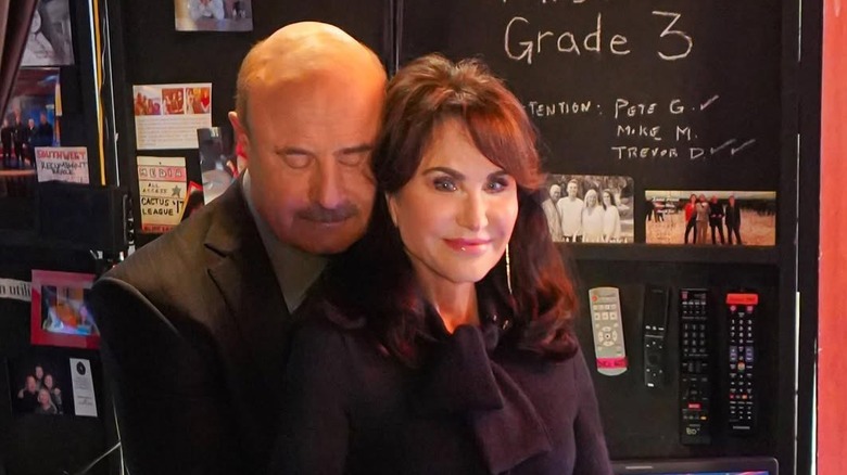 Dr. Phil hugs Robin McGraw with his eyes closed while she smiles