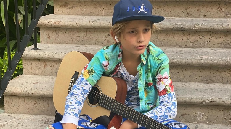 Duke wearing florals and holding a guitar.