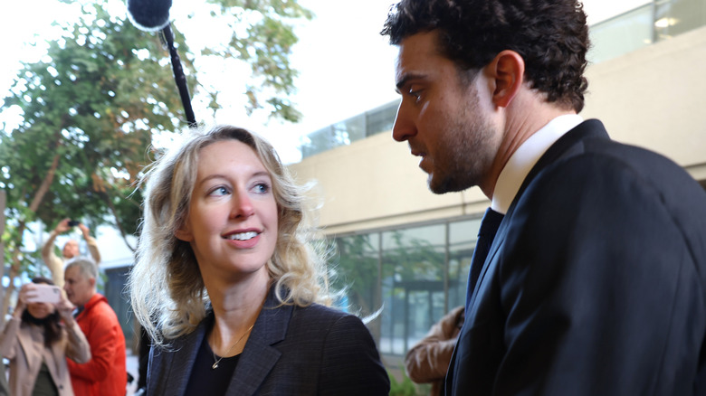Elizabeth Holmes and Billy Evans walking outside with cameras around