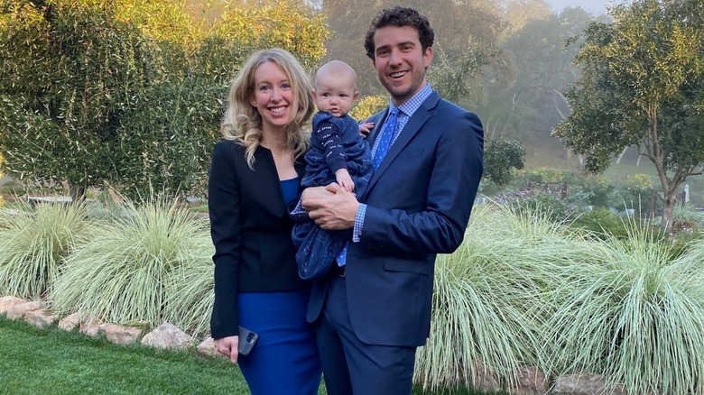 Elizabeth Holmes and Billy Evans posing outdoors with their daughter