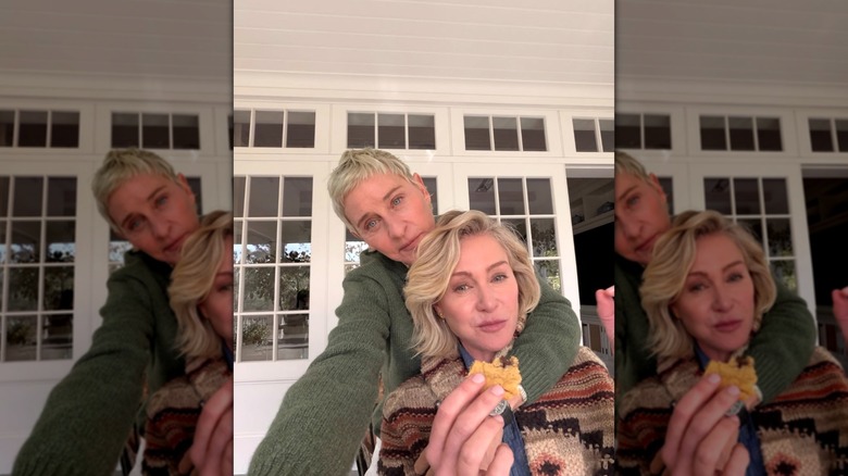 Ellen DeGeneres standing behind Portia de Rossi with her arm around her while posing for a selfie