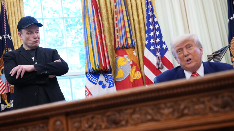 Elon Musk looking at Donald Trump in the Oval Office
