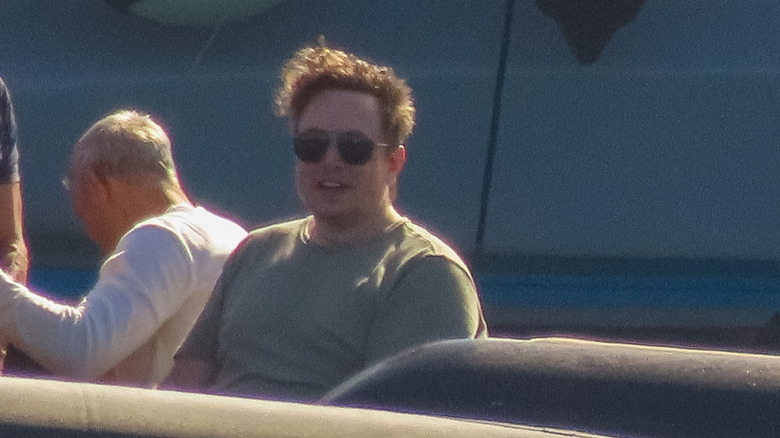 Elon Musk wearing sunglasses and sitting on a boat