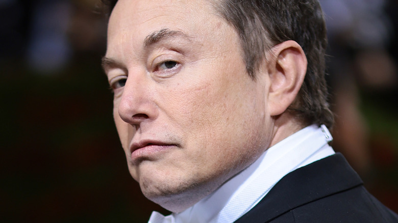 Elon Musk slicked back hair looking over shoulder