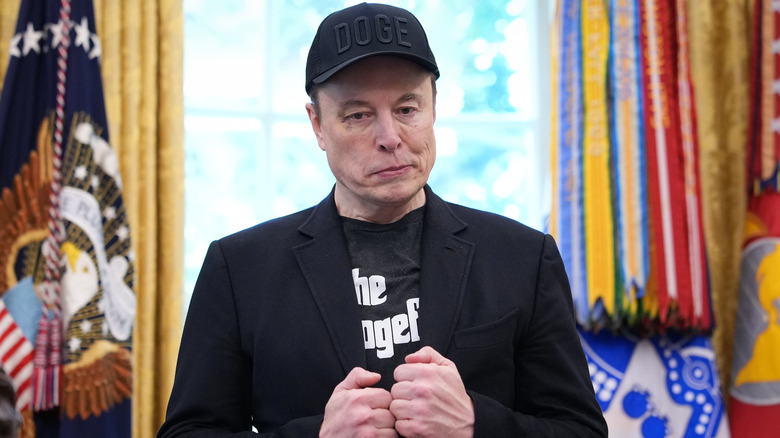 Elon Musk adjusting his jacket while in the Oval Office.