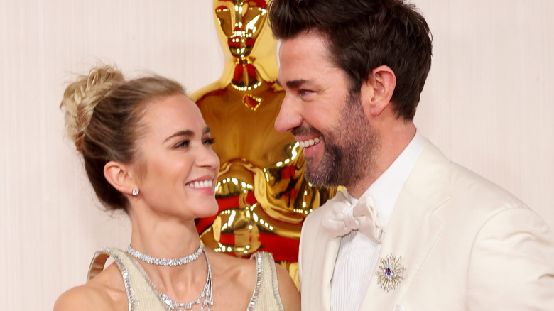 Emily Blunt and John Kraskinski smiling in front of Oscar statue