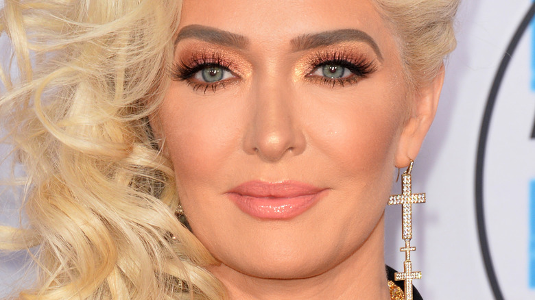 Erika Jayne poses in a drop cross earring