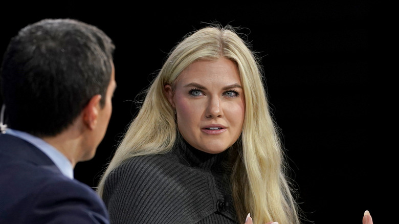 Erika Kirk speaking onstage in a grey sweater