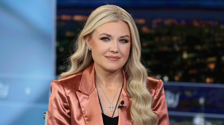 Erika Kirk wears a satin suit jacket and cross necklace.