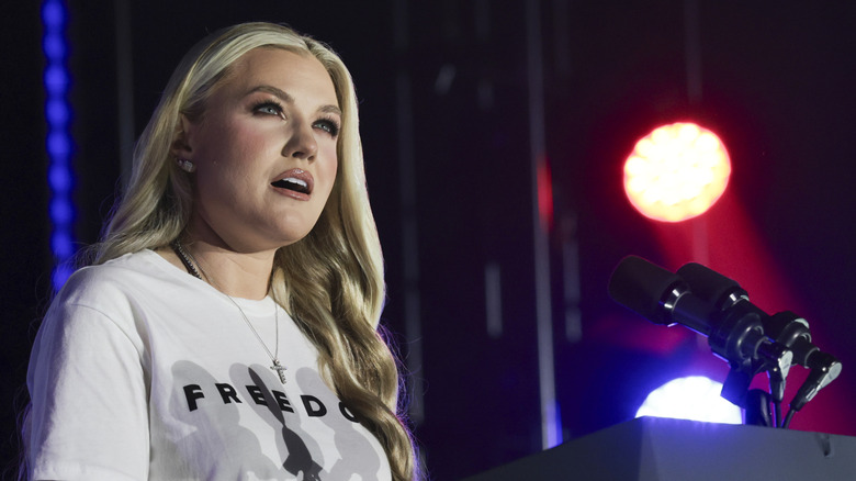Erika Kirk speaking in a white Freedom shirt.