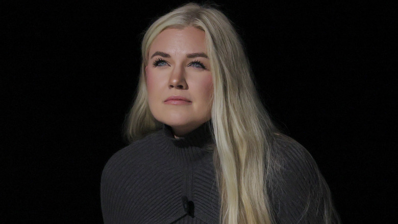 Erika Kirk squinting with downturned lips and wearing a gray turtleneck sweater