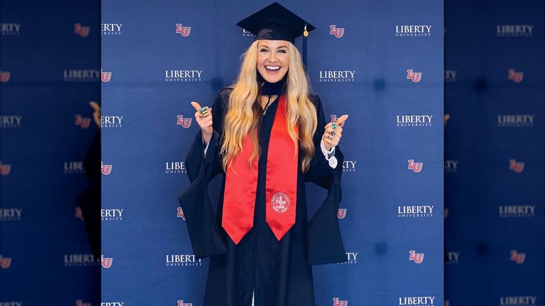 Erika Kirk giving a thumbs up for a photo while wearing her cap and gown