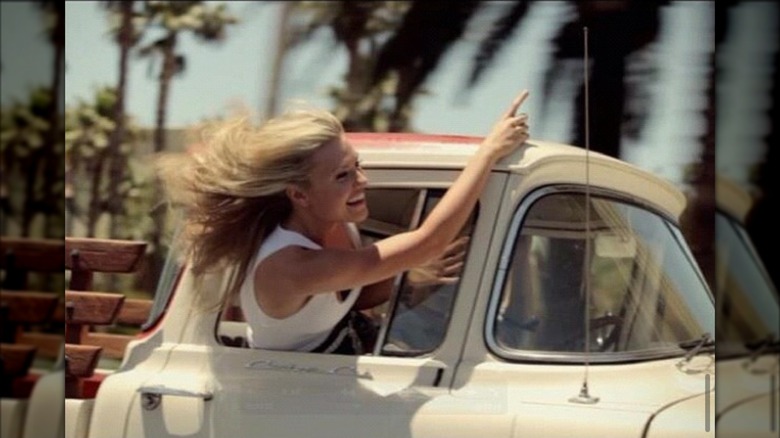 Erika Kirk hanging out of a pickup truck while filming a music video