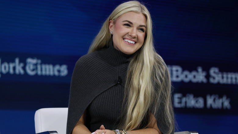 Erika Kirk smiling in a brown sweater