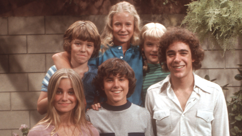 Eve Plumb smiling with her fellow Brady Bunch siblings