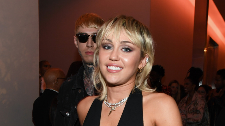 Miley Cyrus with blonde bangs and pearl necklace