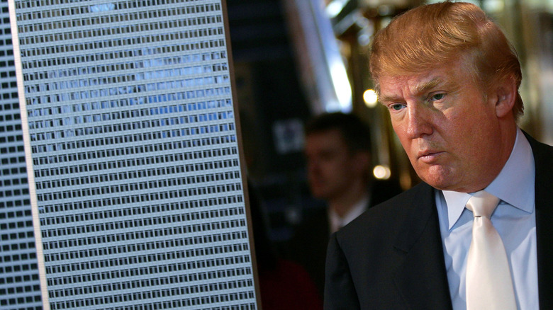 Donald Trump frowning beside building model