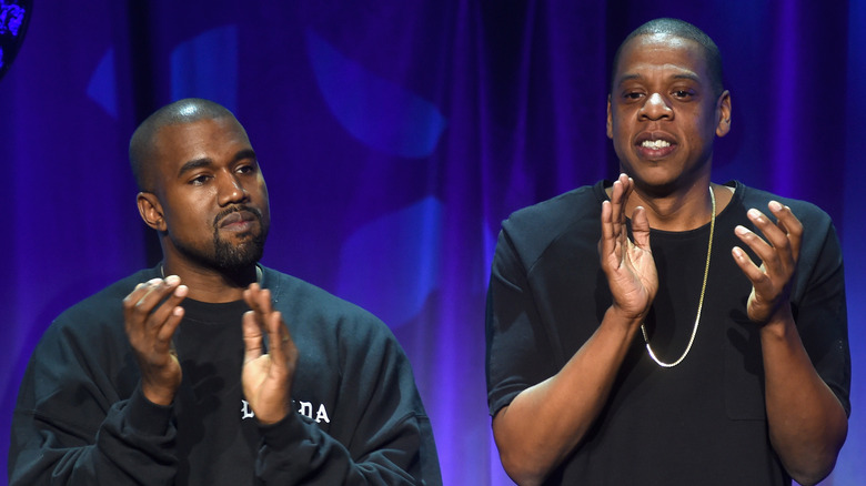 Kanye West applauding beside Jay Z