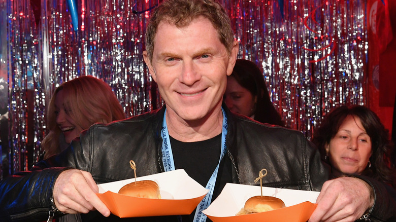 Bobby Flay holding burgers 