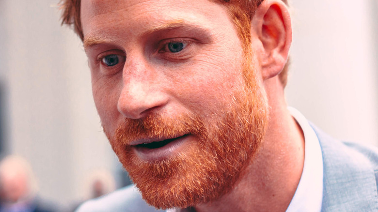 Prince Harry talks to the public in light gray suit