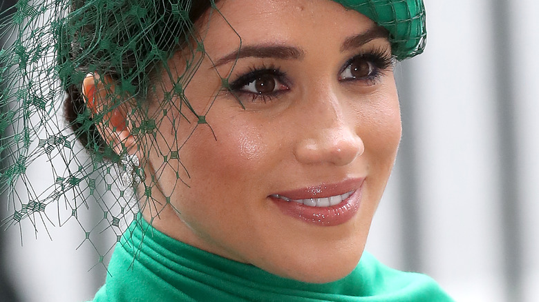 Meghan Markle smiling in green fascinator