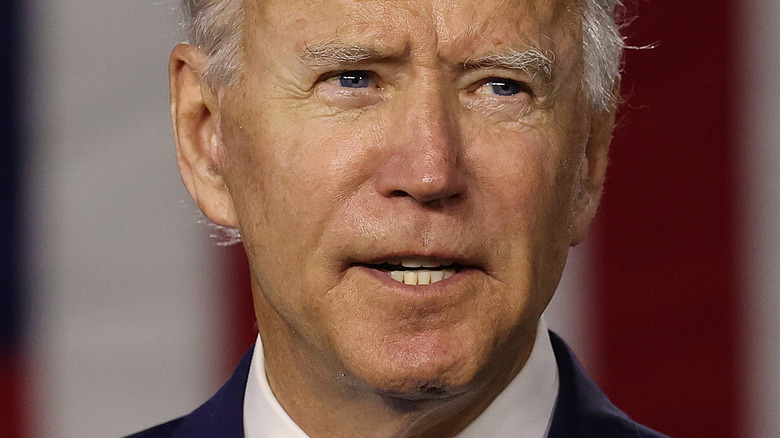 Joe Biden with serious expression in front of American flag