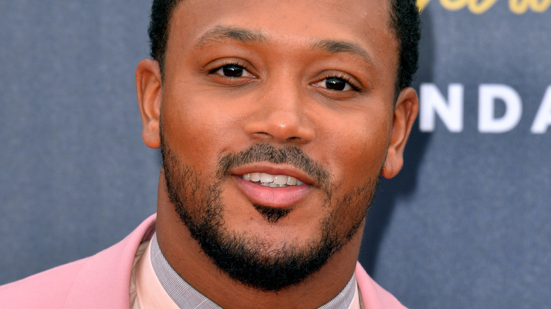 Romeo Miller smiles on red carpet