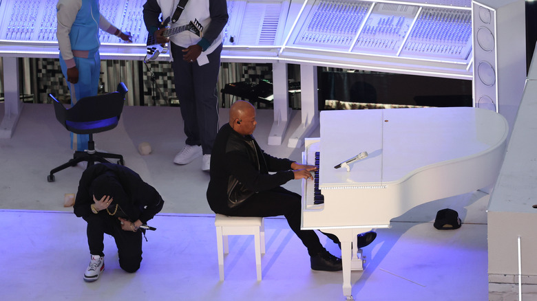 Dr. Dre playing the piano and Eminem taking a knee