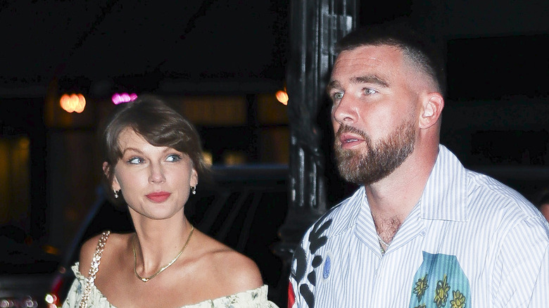 Taylor Swift looking sideways at a worried-seeming Travis Kelce